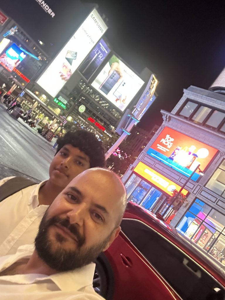 Baljinder Singh and Rajbir Singh in a brightly lit Toronto square at night.